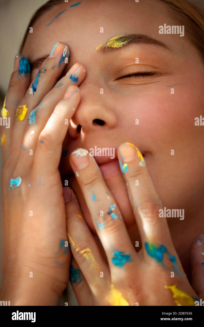 Closeup foto di una ragazza sognante con occhi chiusi e mani colorate in vernice, pittori mondo interno, foto concettuale di artisti creativi con una nuova idea Foto Stock