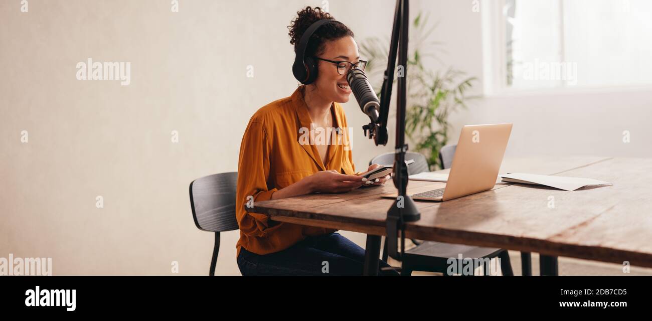 Podcaster donna che fa un podcast da casa studio. Donna che lavora da casa registrando un podcast su un laptop. Foto Stock