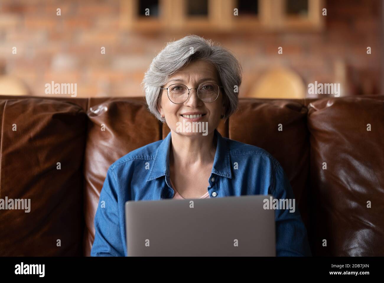 Ritratto della testa sorridente donna matura indossando occhiali che tengono un computer portatile Foto Stock