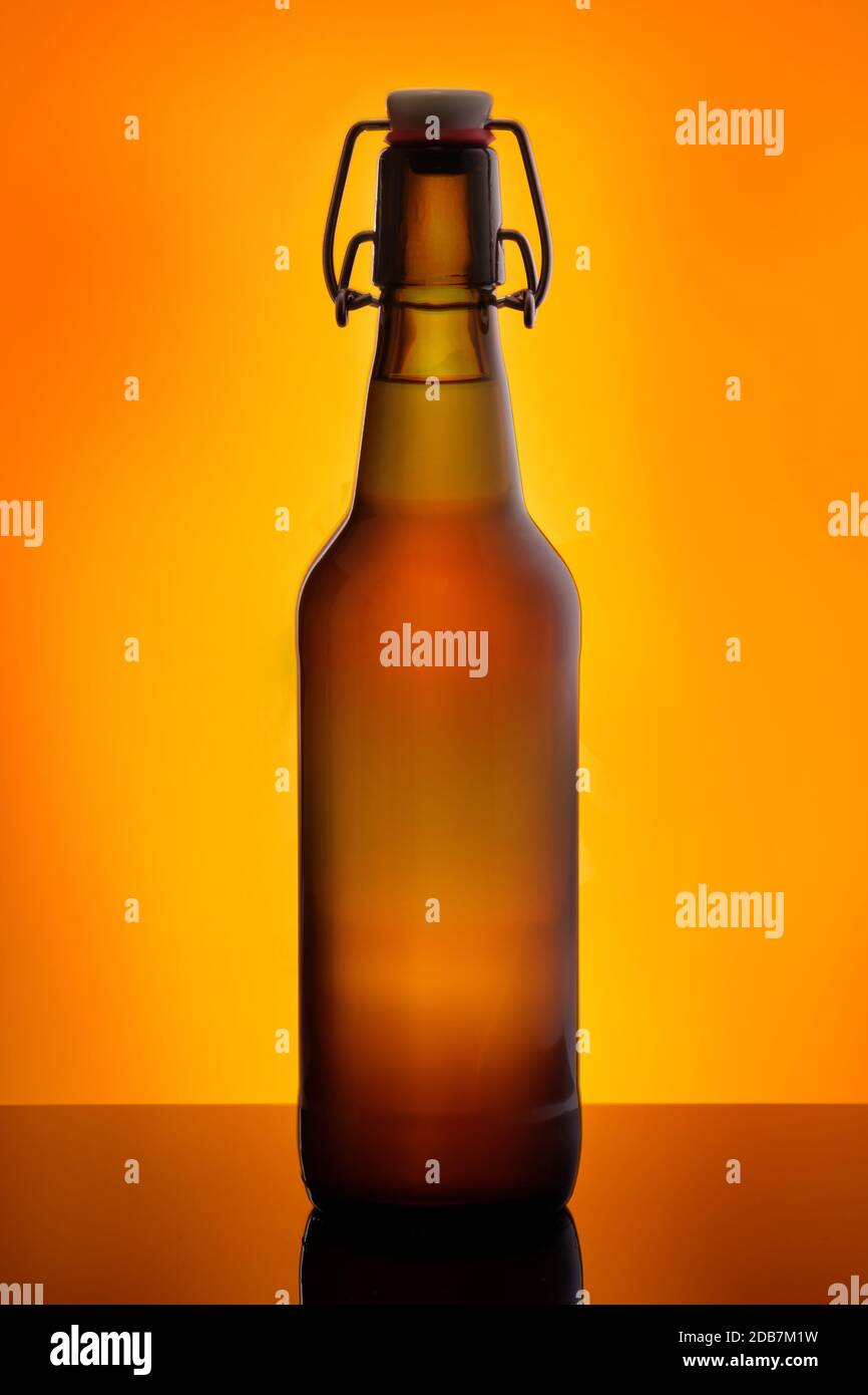 Birra bruna bootle con swing top in arancione back lit Foto Stock