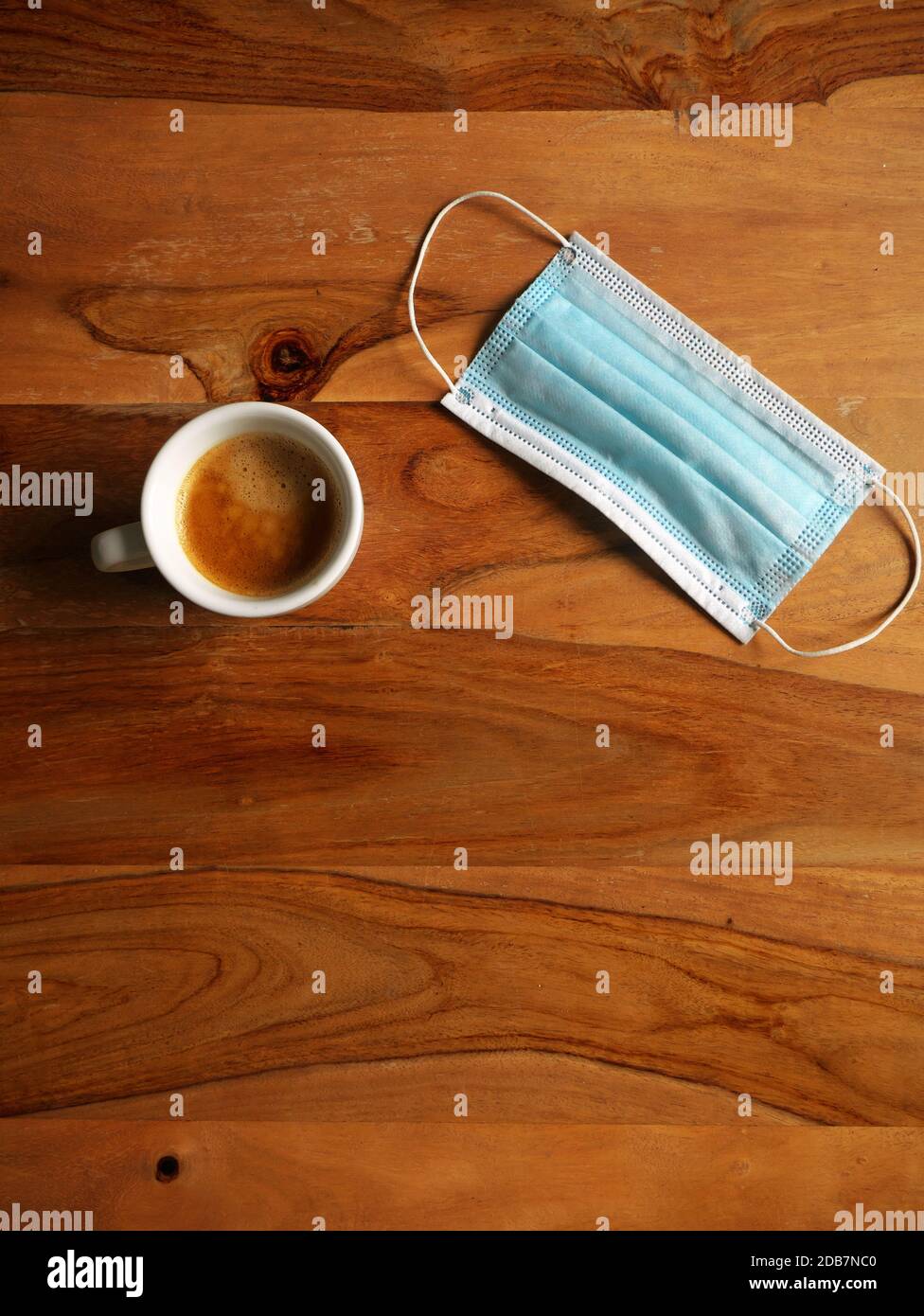 Tazza di caffè posta su un tavolo di legno accanto ad una maschera. Vista dall'alto Foto Stock
