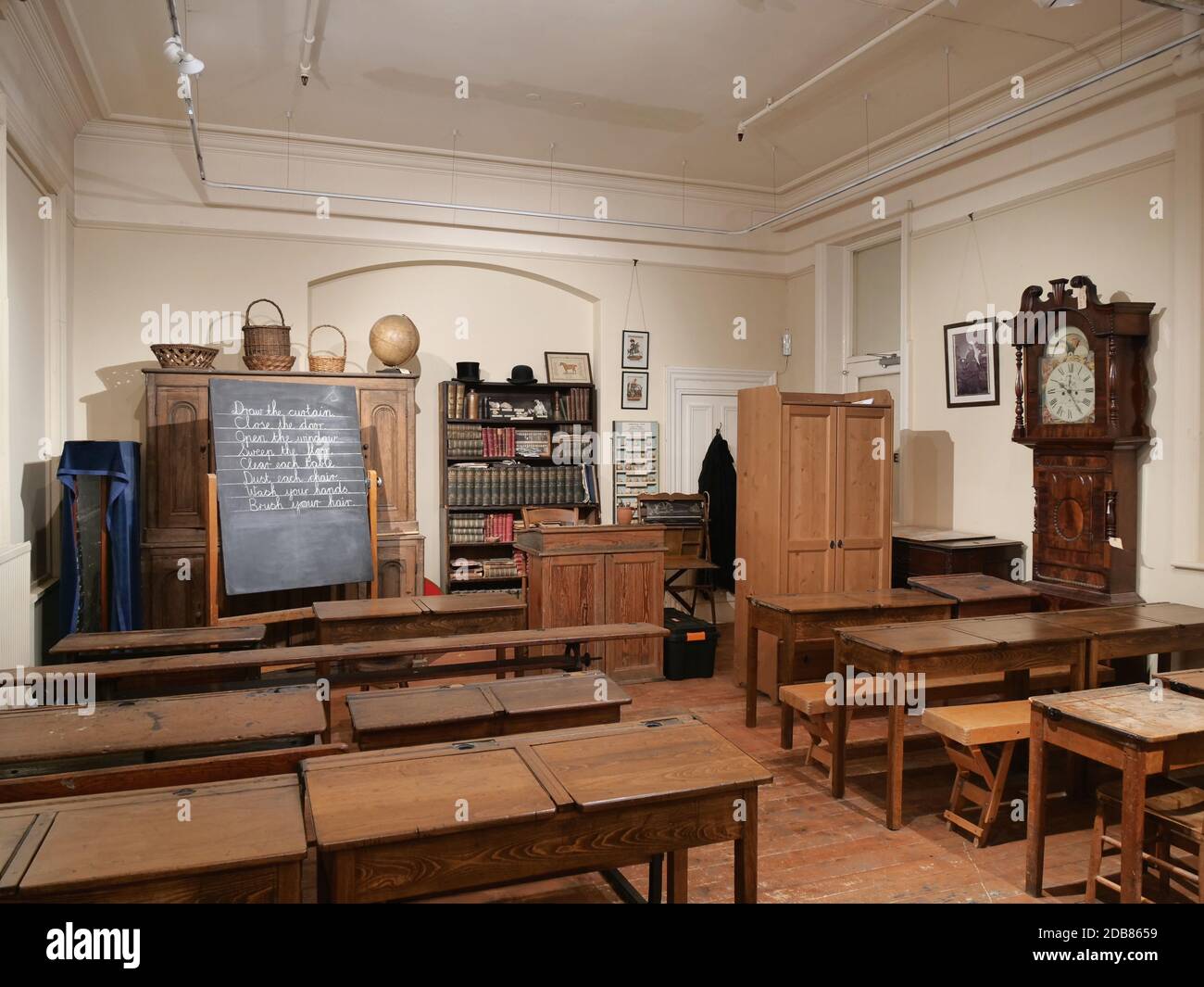 Sala museo scrivanie lavagna alto libro orologio scaffali posti a sedere armadio in legno pavimento in legno Foto Stock