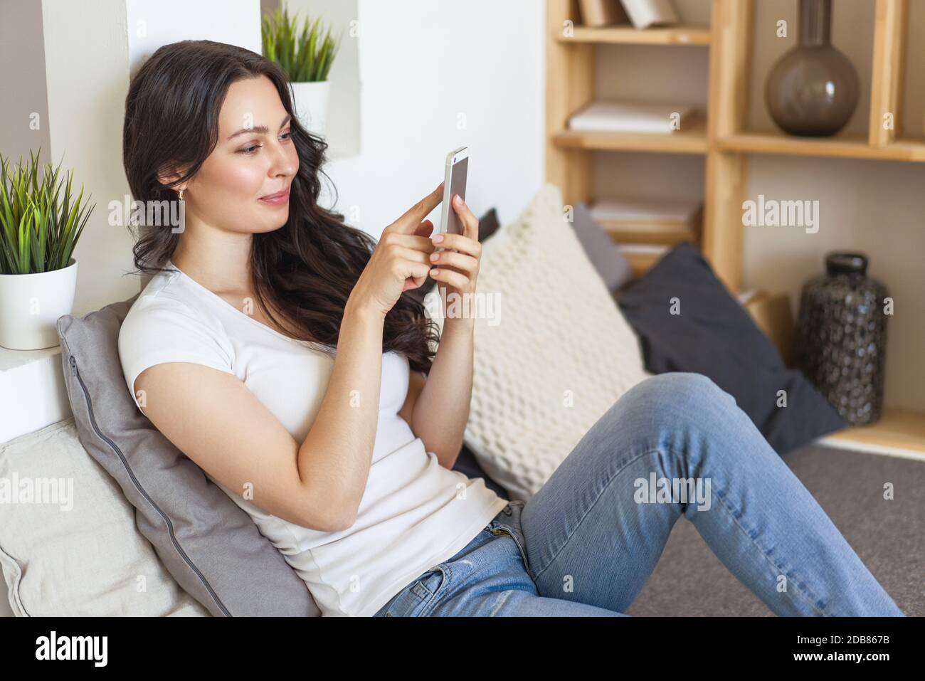 Carino donna felice che tiene il cellulare, utilizzando l'applicazione di incontri mobili per chattare o inviare messaggi. Foto Stock