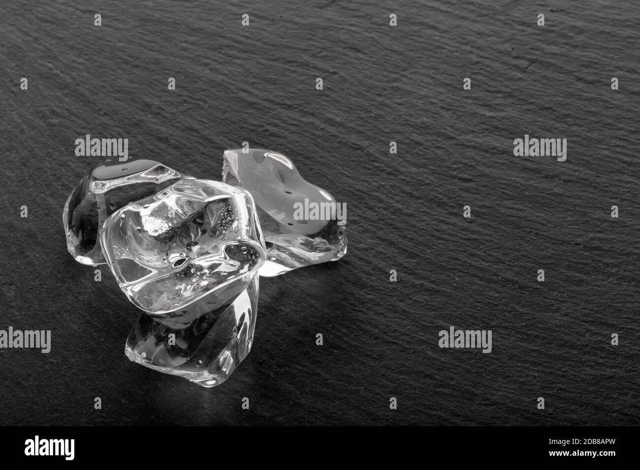Cubetti di ghiaccio di grandi dimensioni con goccioline su tavola nera in  ardesia. Copiare lo spazio Foto stock - Alamy