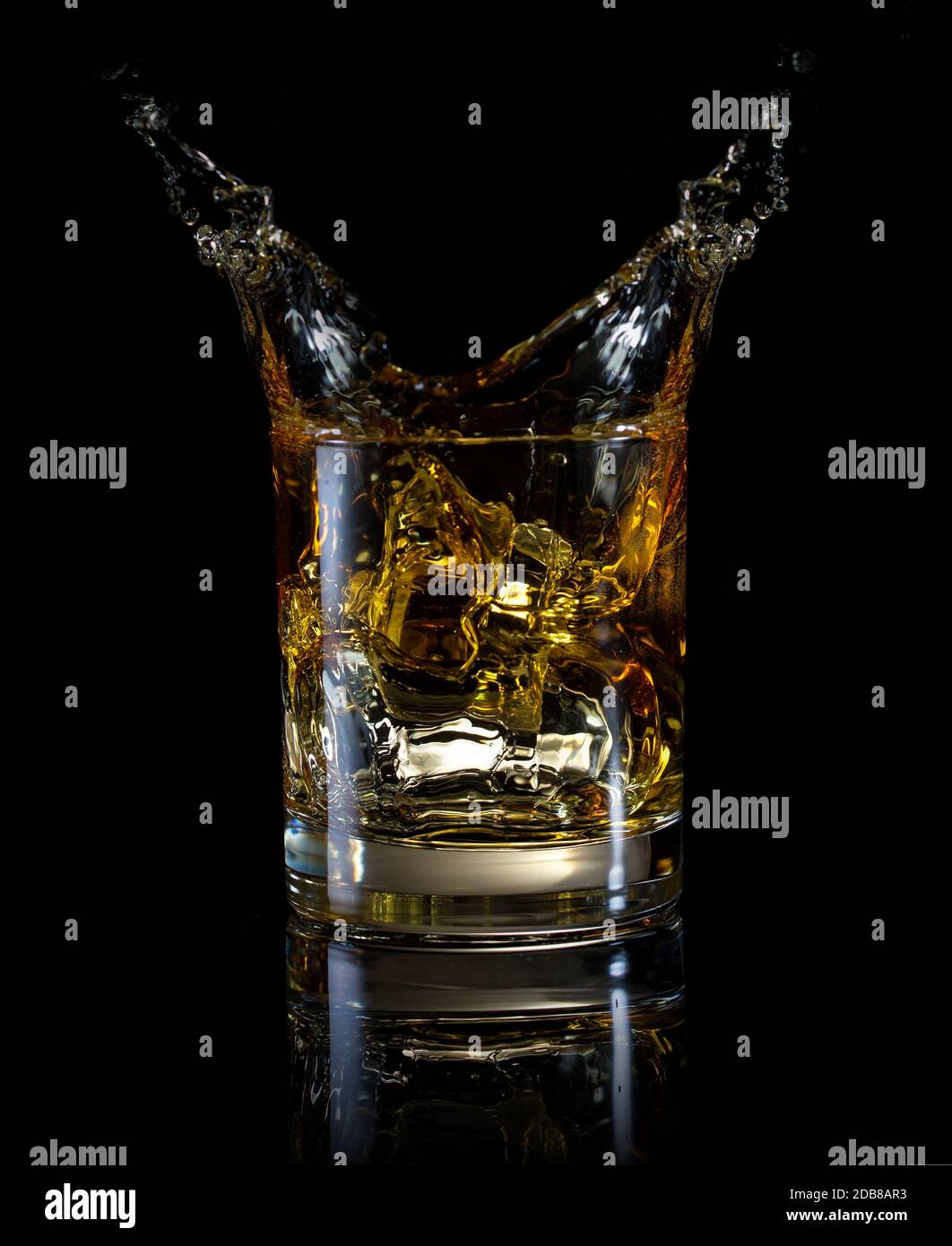 Un bicchiere di whiskey e splash isolata su uno sfondo nero Foto Stock