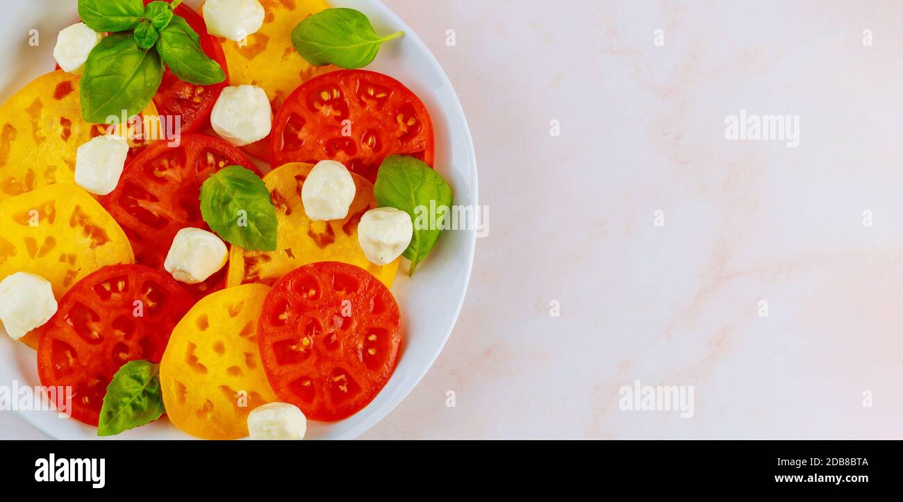 Mozzarella, basilico e pomodoro su piatto bianco. Primo piano della vista superiore. Foto Stock