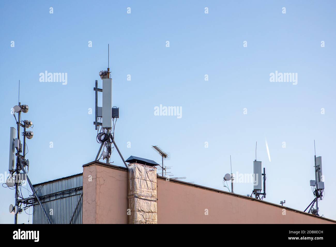 Ripetitori di comunicazione mobile sul tetto di un alto edificio contro il cielo blu. Spazio di copia Foto Stock