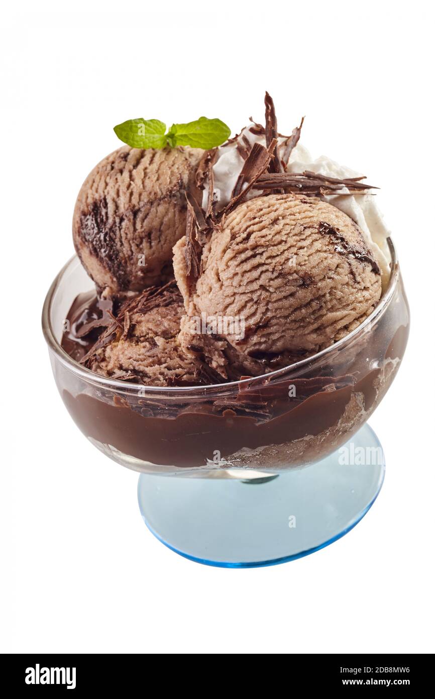 Scoop di gelato al cioccolato guarnito con fiocchi e foglie di menta fresca in un piatto di vetro a piedistallo isolato su bianco Foto Stock