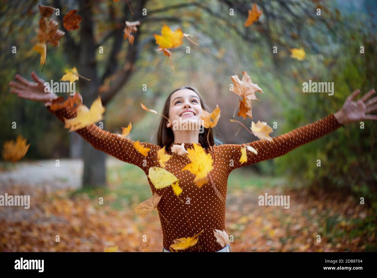 Ritratto di una ragazza sorridente che lancia foglie autunnali nell'aria, Bulgaria Foto Stock