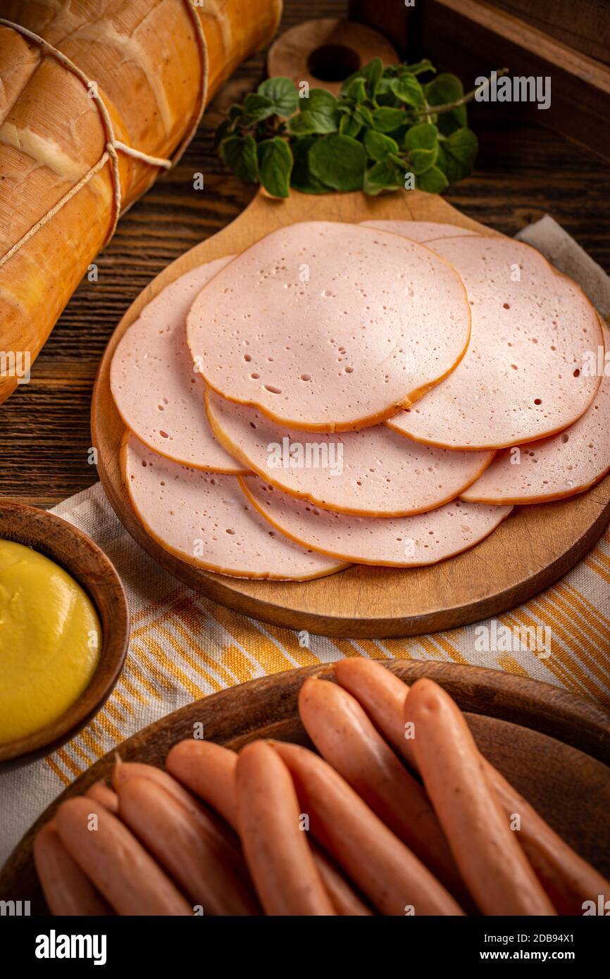 Prodotti a base di carne fredda e salsicce di cane caldo su tagliere di legno Foto Stock