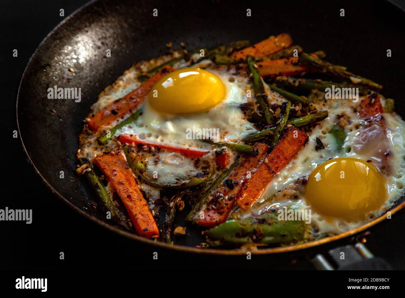 Molto grossolanamente due uova fritte in una padella con grandi fette di  carote, peperoni e asparagi con spezie e salsa Foto stock - Alamy
