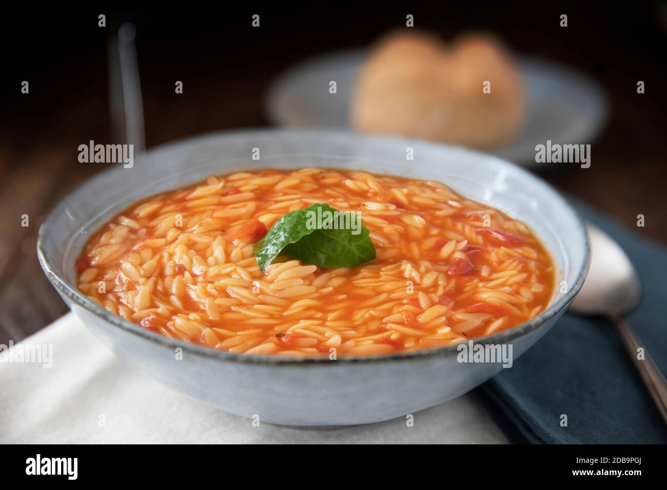 Ciotola di pasta all'orzo e zuppa di pomodoro con basilico Foto Stock