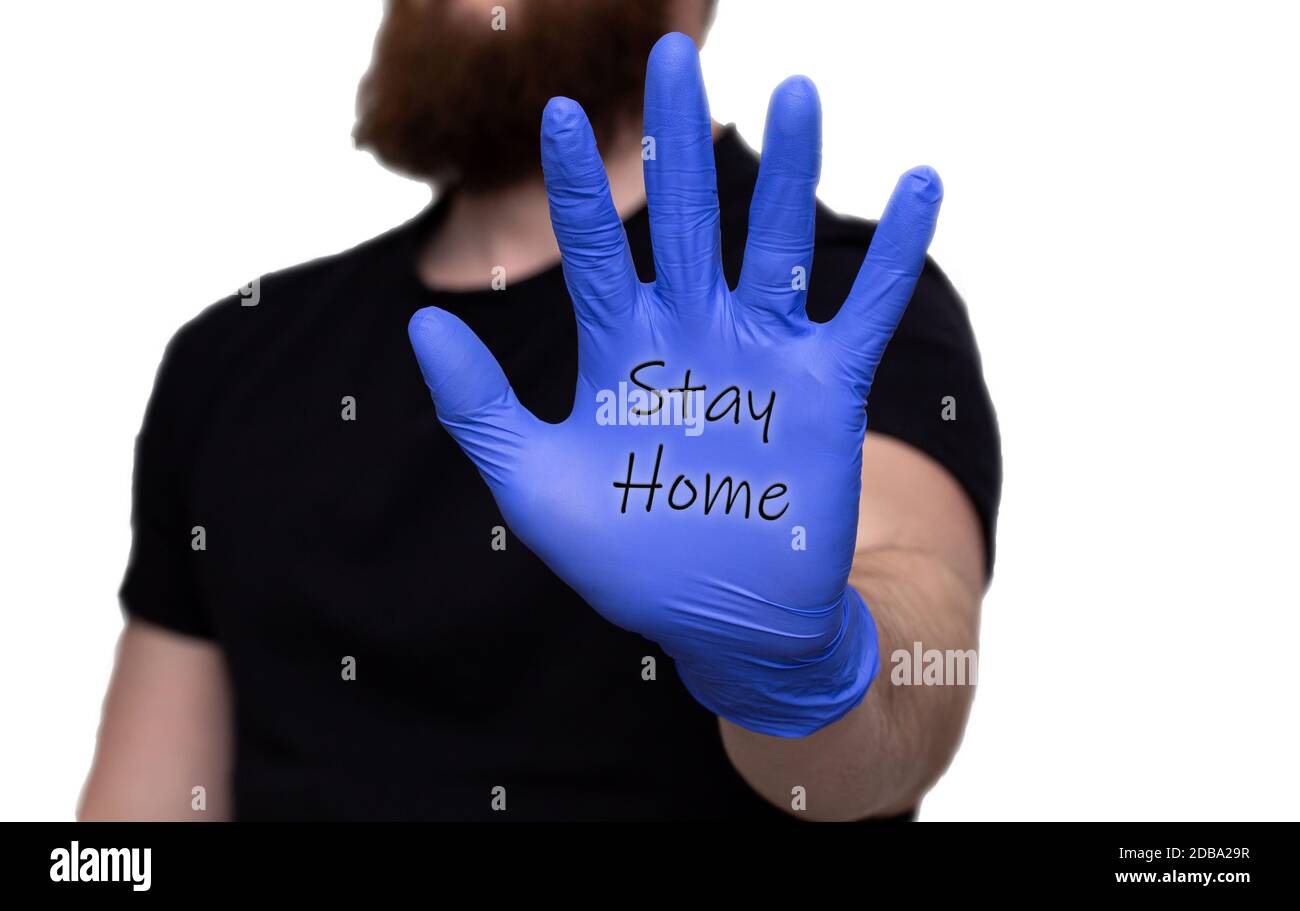 Mano dell'uomo in guanti blu medico con le parole Stay Home, autoisolamento o quarantena covid-19 coronavirus Stop Foto Stock