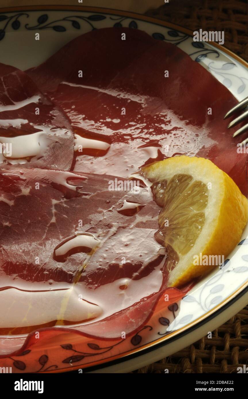 Fette di bresaola con succo di limone e olio d'oliva Foto Stock