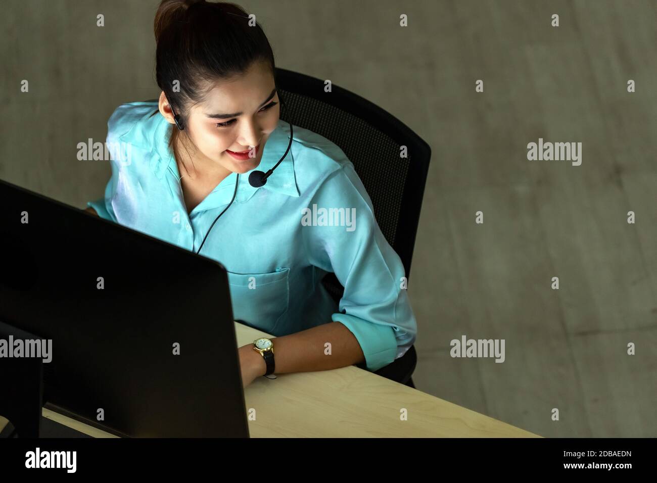 Ambiente di tarda notte. Vista dall'alto di una ragazza del call center per adulti con cuffie e auricolari che lavorano sodo di notte. Utilizzo per 24 ore. 7 giorni Foto Stock