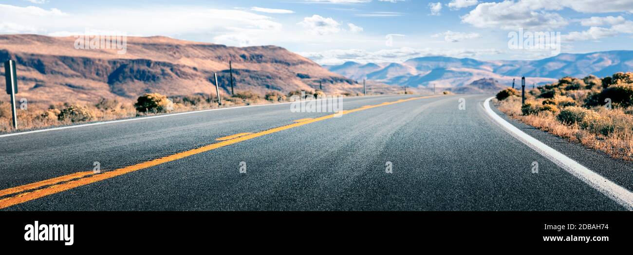 Lunga strada attraverso il deserto, strada vuota che conduce alle montagne, due corsie percorso asfaltato Foto Stock
