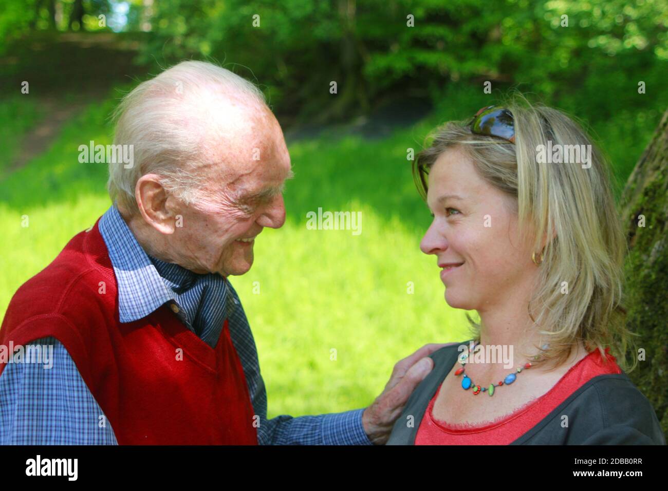 Felice uomo di 90 anni e giovane donna sorridente guardando nei loro occhi Foto Stock