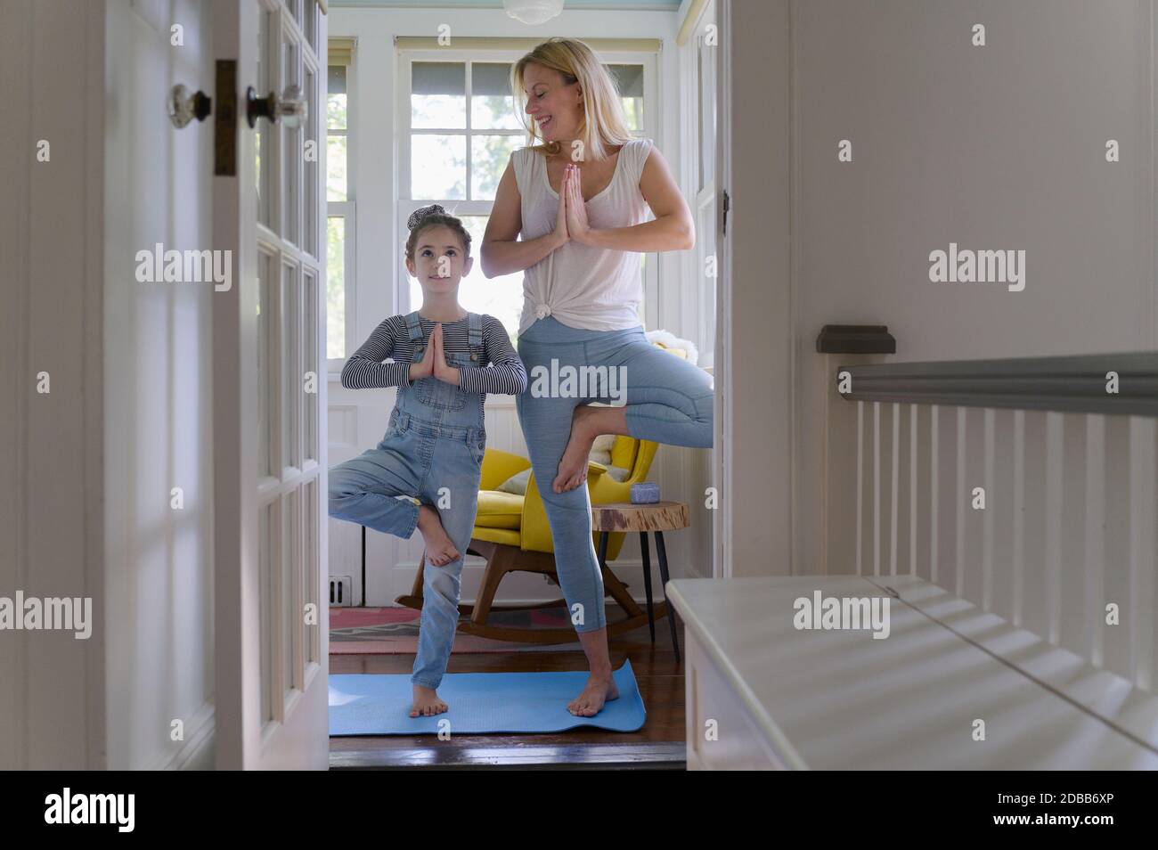 Madre con figlia (6-7) che pratica yoga insieme a casa Foto Stock