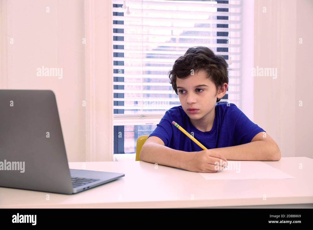 Ragazzo (8-9) seduto alla scrivania a casa durante la lezione remota Foto Stock