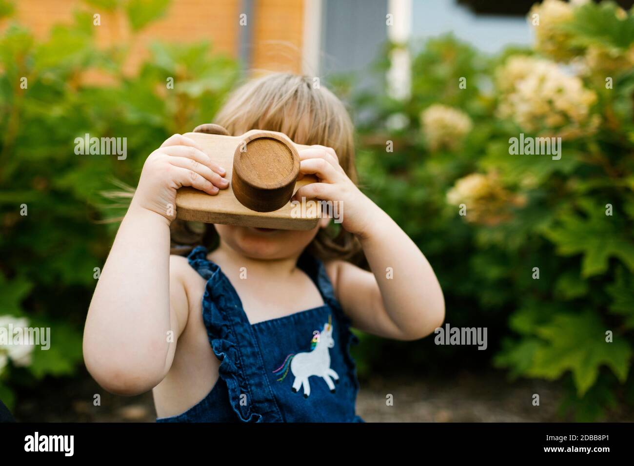 Bambina (2-3) con macchina fotografica giocattolo in giardino Foto Stock