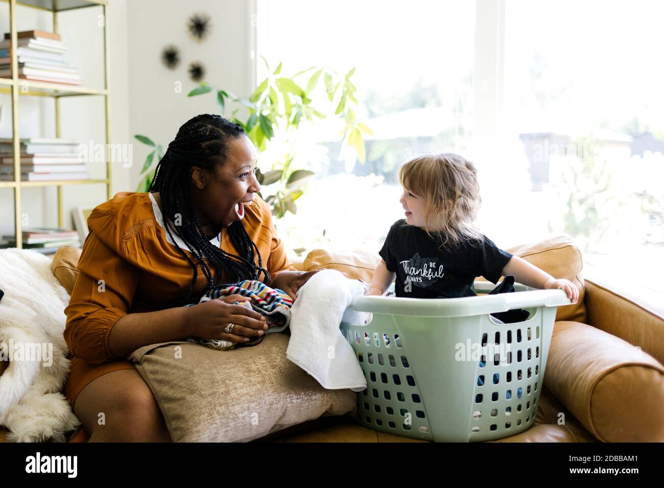 Donna che gioca con la bambina (2-3) seduta nel cesto di bucato Foto Stock