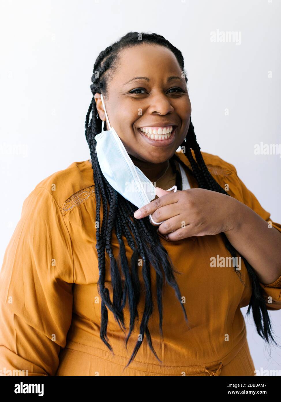 Studio ritratto di donna sorridente che regge maschera facciale protettiva Foto Stock