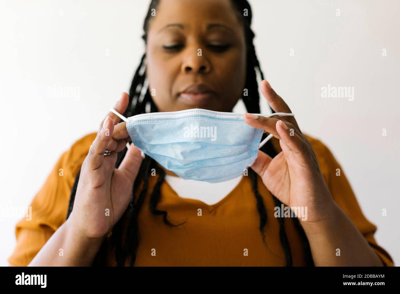 Studio ritratto di donna che mette sulla maschera protettiva del viso Foto Stock