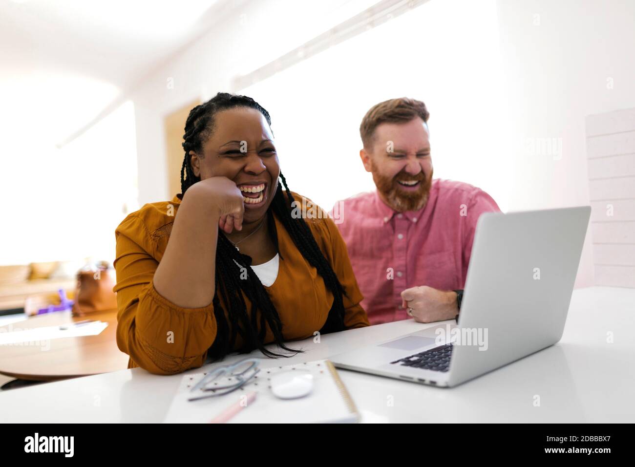 Uomo e donna sorridenti che guardano il computer portatile alla scrivania ufficio domestico Foto Stock