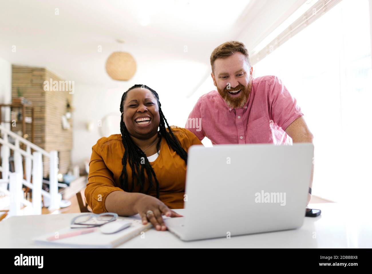 Uomo e donna che guardano il computer portatile alla scrivania a casa ufficio Foto Stock