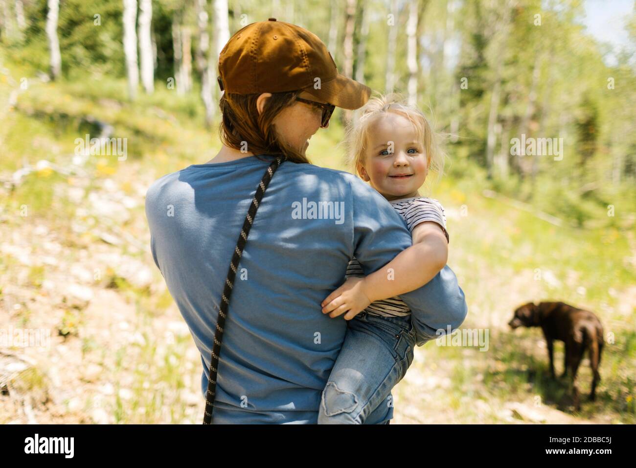 Vista posteriore della donna che porta la figlia (2-3) in paesaggio Foto Stock