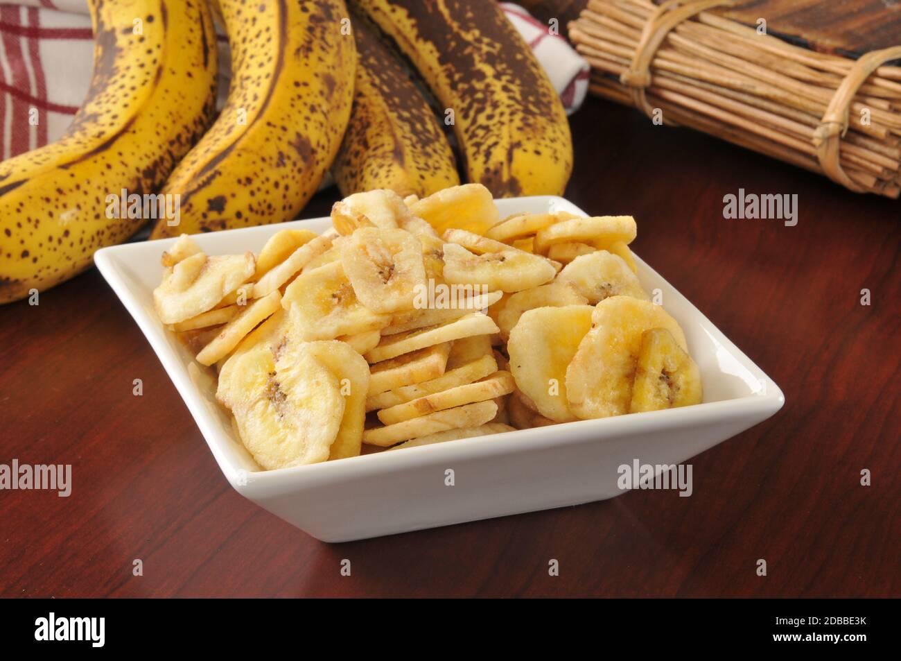 una ciotola di gocce di banana essiccate su un tavolo di legno Foto Stock