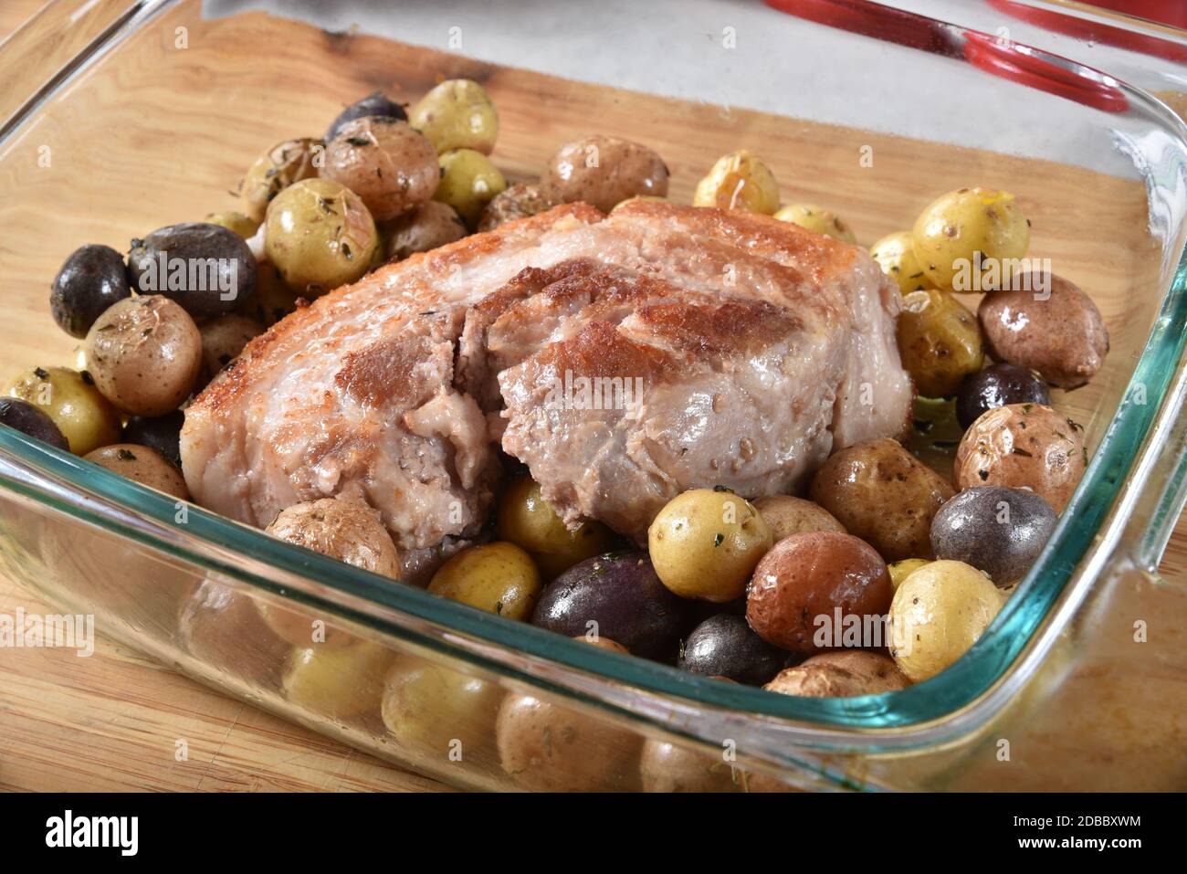 Un succulento arrosto di pancia di maiale con patate minuscole Foto Stock