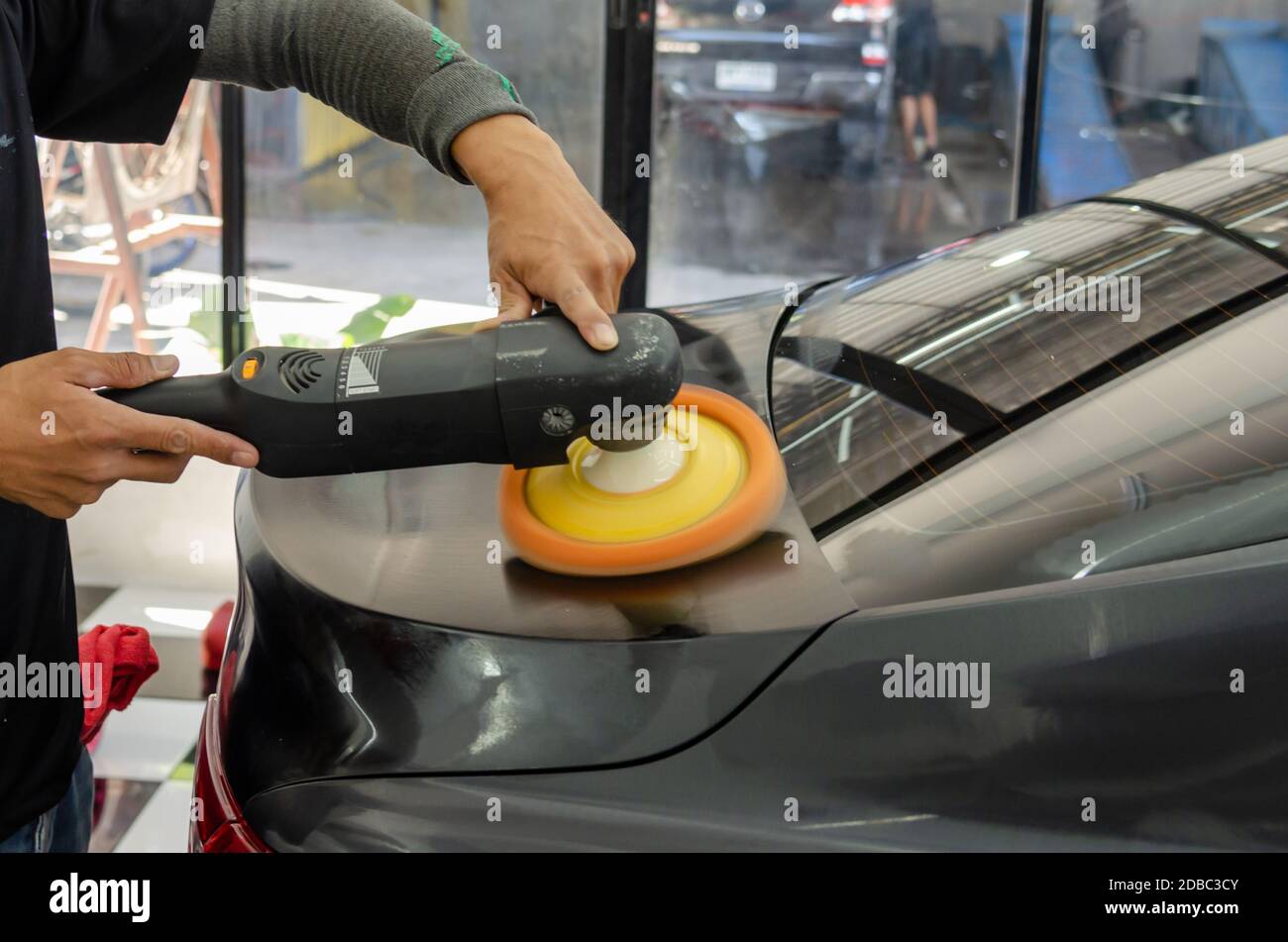 Uomo che lavora per la lucidatura, rivestimento automobili. la lucidatura delle auto potrà aiutare a eliminare i contaminanti sulla superficie della vettura.La ceretta la superficie della vettura sarà c Foto Stock