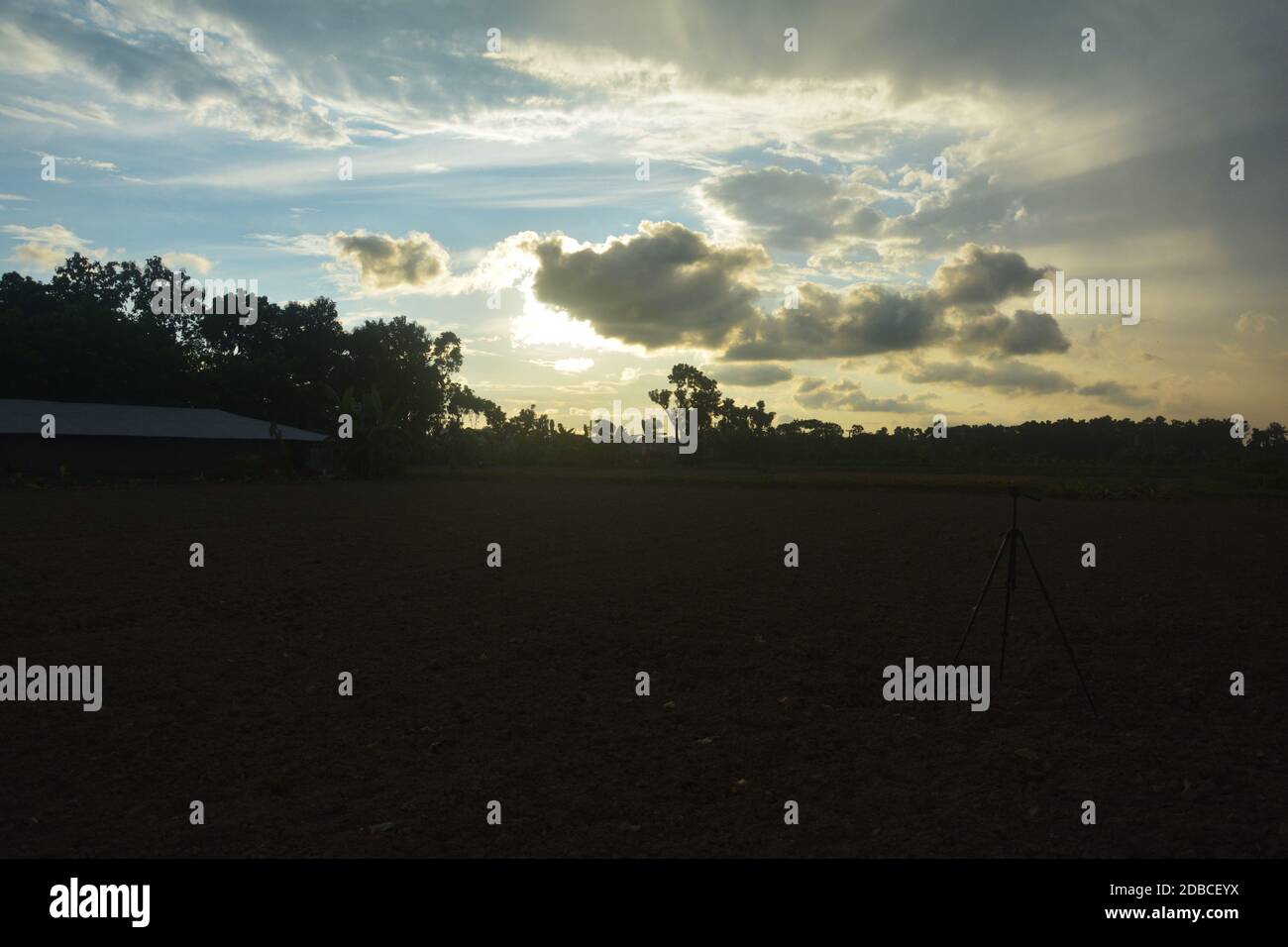 La scena di un campo villaggio con cielo blu e. sole dietro le nuvole Foto Stock