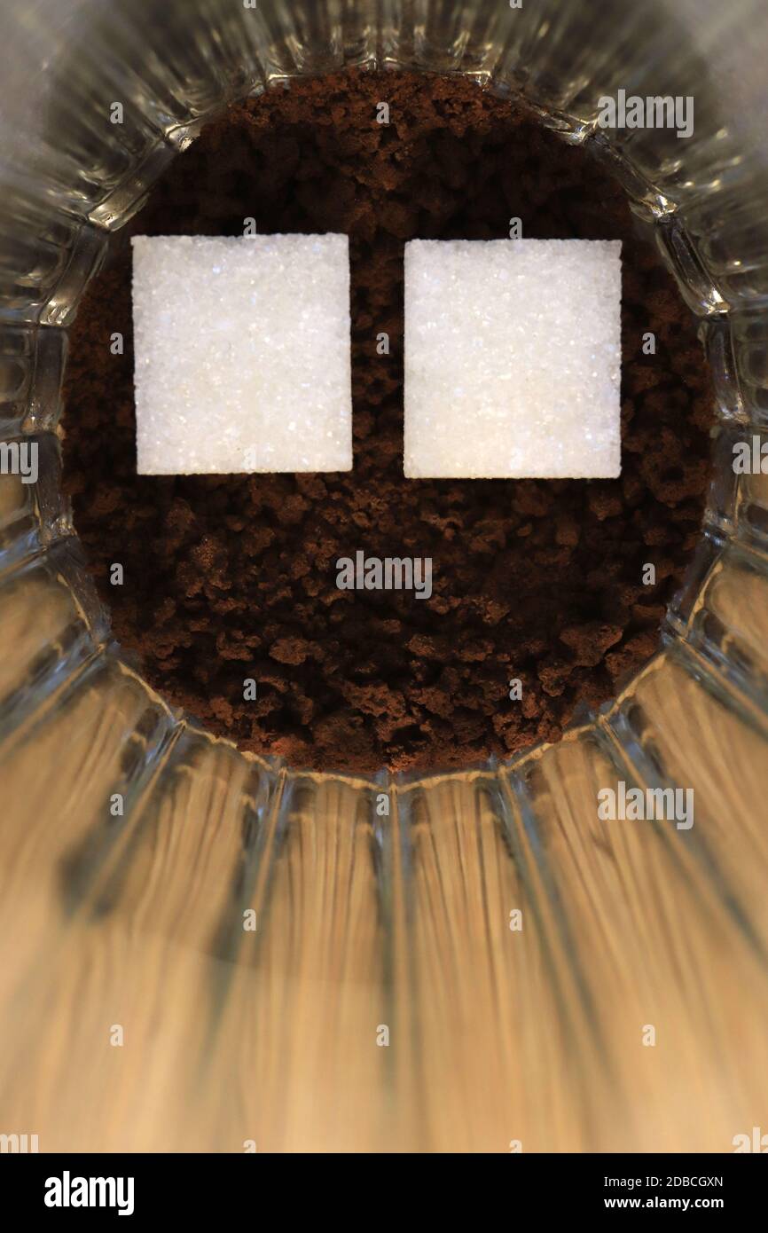 Due pezzi di zucchero in un bicchiere con un caffè insolubile Foto Stock