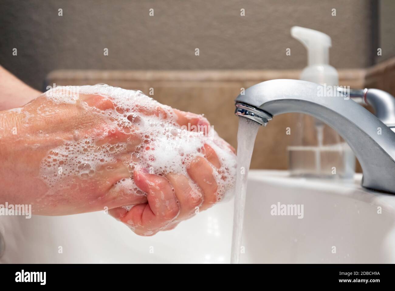 Lavando le mani con sapone e acqua nel lavello del bagno, protezione contro virus e batteri, igiene per rimanere in buona salute Foto Stock