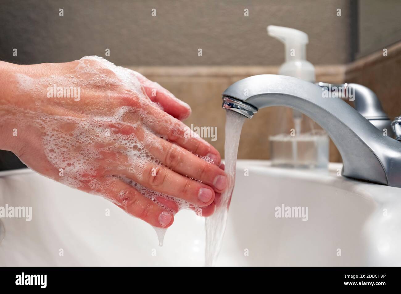 Lavando le mani con sapone e acqua nel lavello del bagno, protezione contro virus e batteri, igiene per rimanere in buona salute Foto Stock
