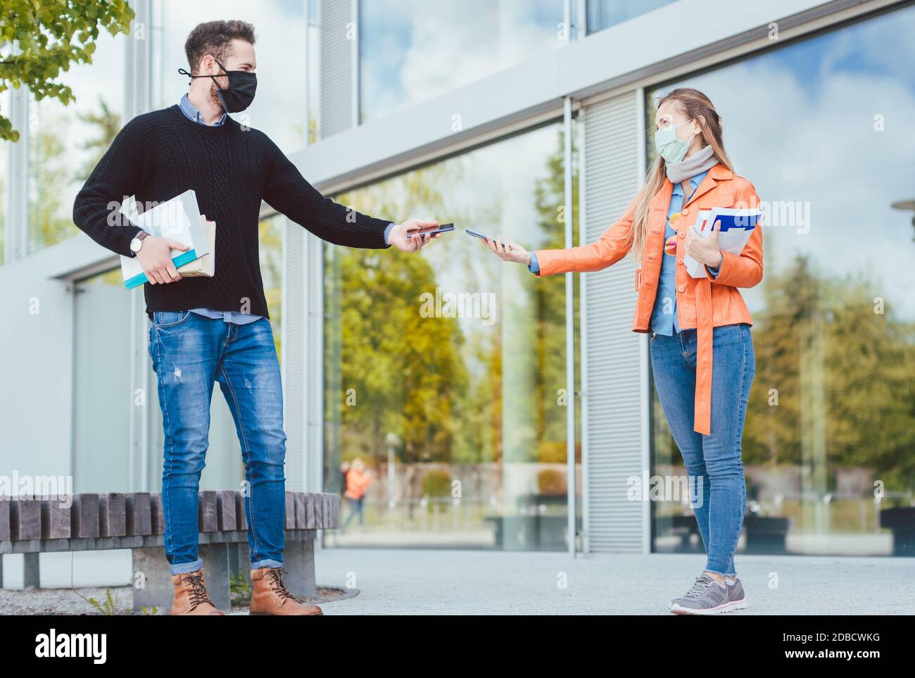 Due studenti durante crisi di coronavirus con telefoni cellulari e contratto applicazione tracing Foto Stock