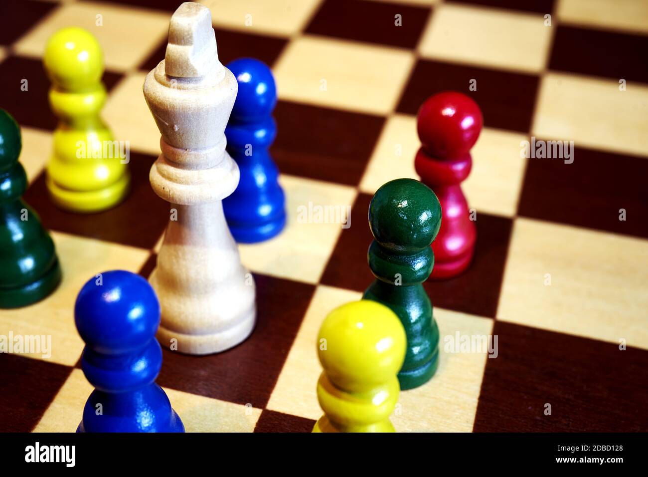 concetto di scacchi alla diversificazione, pegni colorati huddle intorno al grande vecchio re bianco Foto Stock