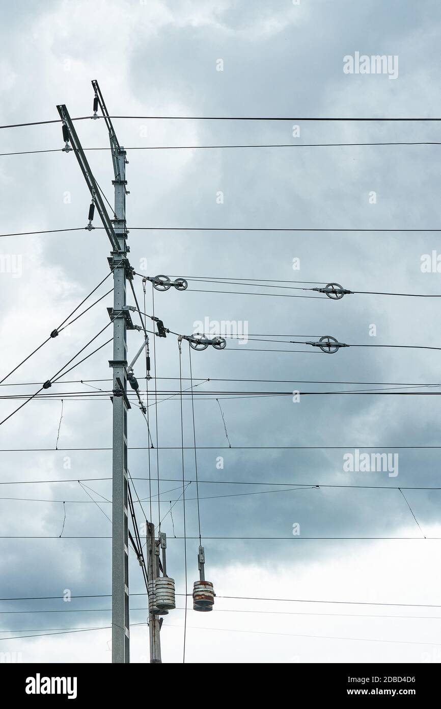 Fili di contatto sospesi di binari elettrificati contro un cielo cupo. Tensione del filo Foto Stock