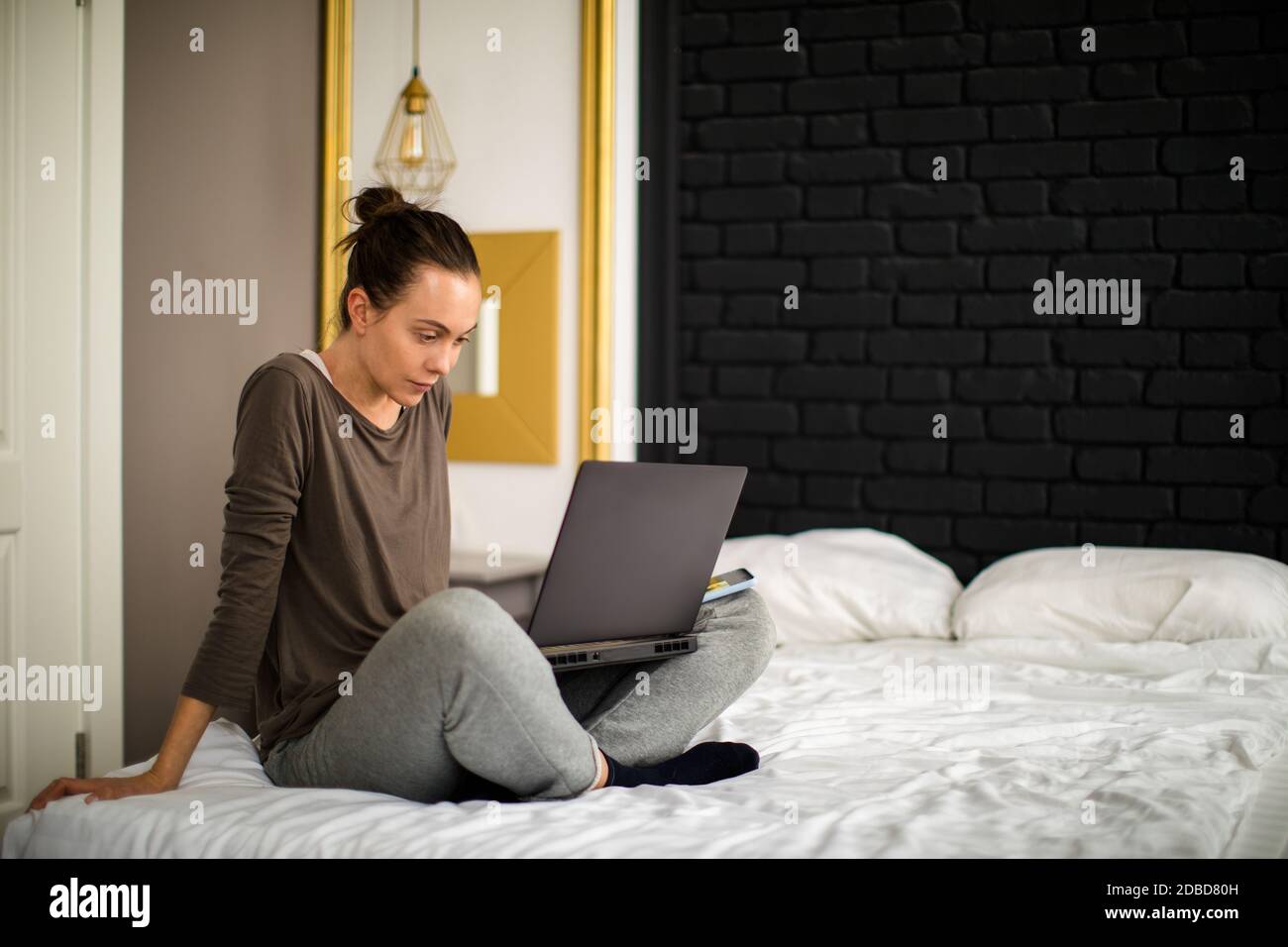 Donna adulta che usa il computer portatile a letto Foto Stock