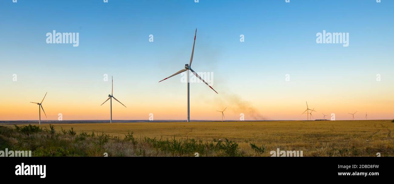 Turbine eoliche fonti di energia rinnovabile paesaggio estivo con blu chiaro cielo al tramonto Foto Stock