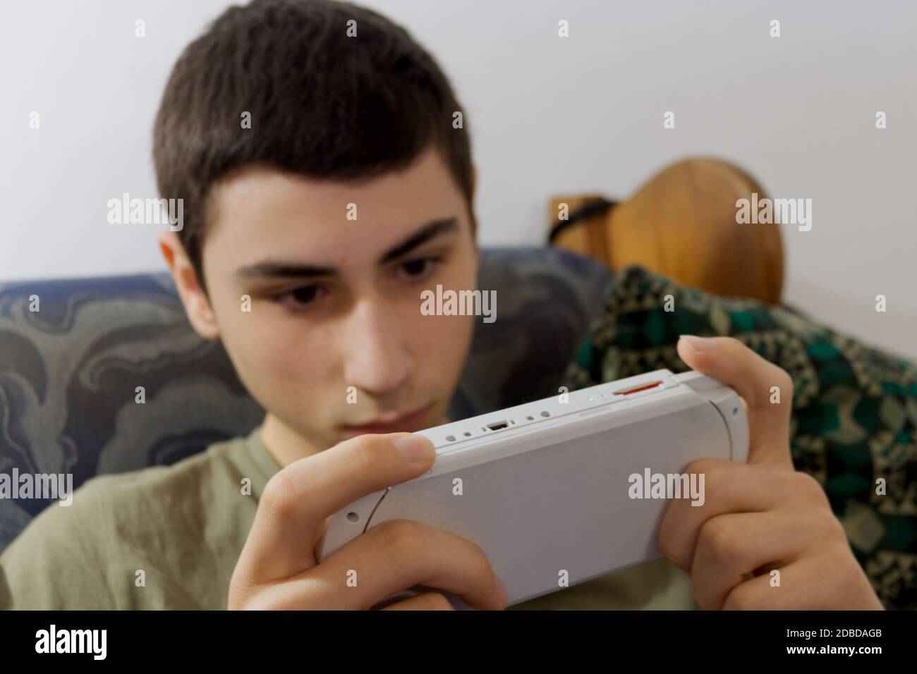 Il ragazzo caucasico gioca con una console portatile sul divano Foto Stock