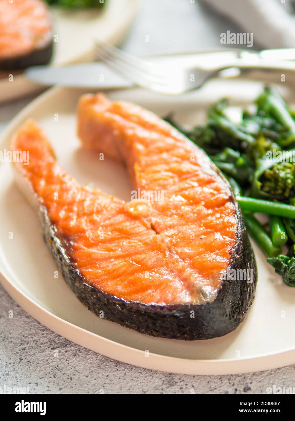 Pronto a mangiare salmone alla griglia bistecca e verdi - baby broccoli o broccolini e spinaci su rustiche piastra artigianali su sfondo grigio. Dieta cheto piatto. Foto Stock
