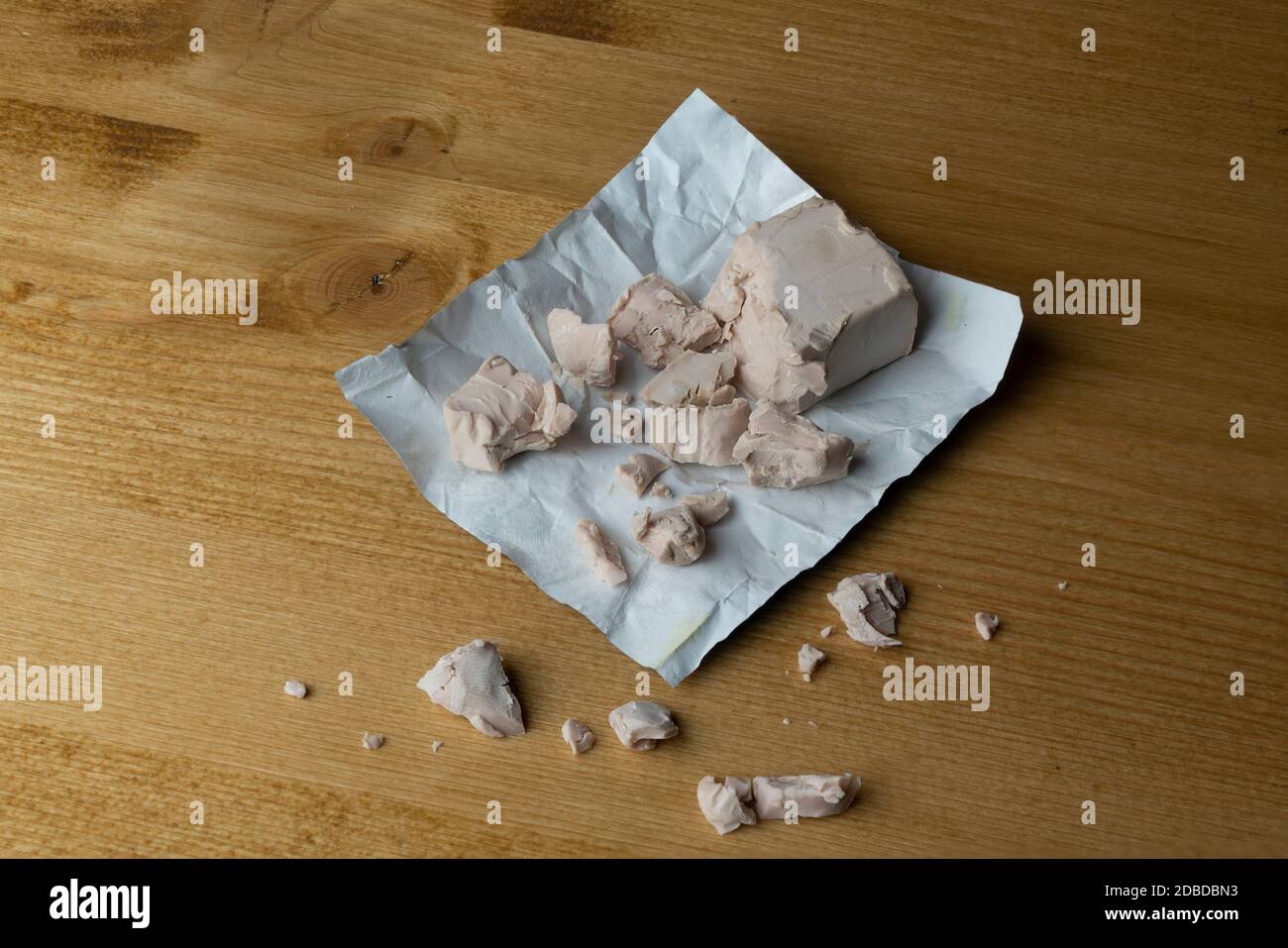 un cubo di lievito di birra si è sbriciolato sul tavolo Foto Stock