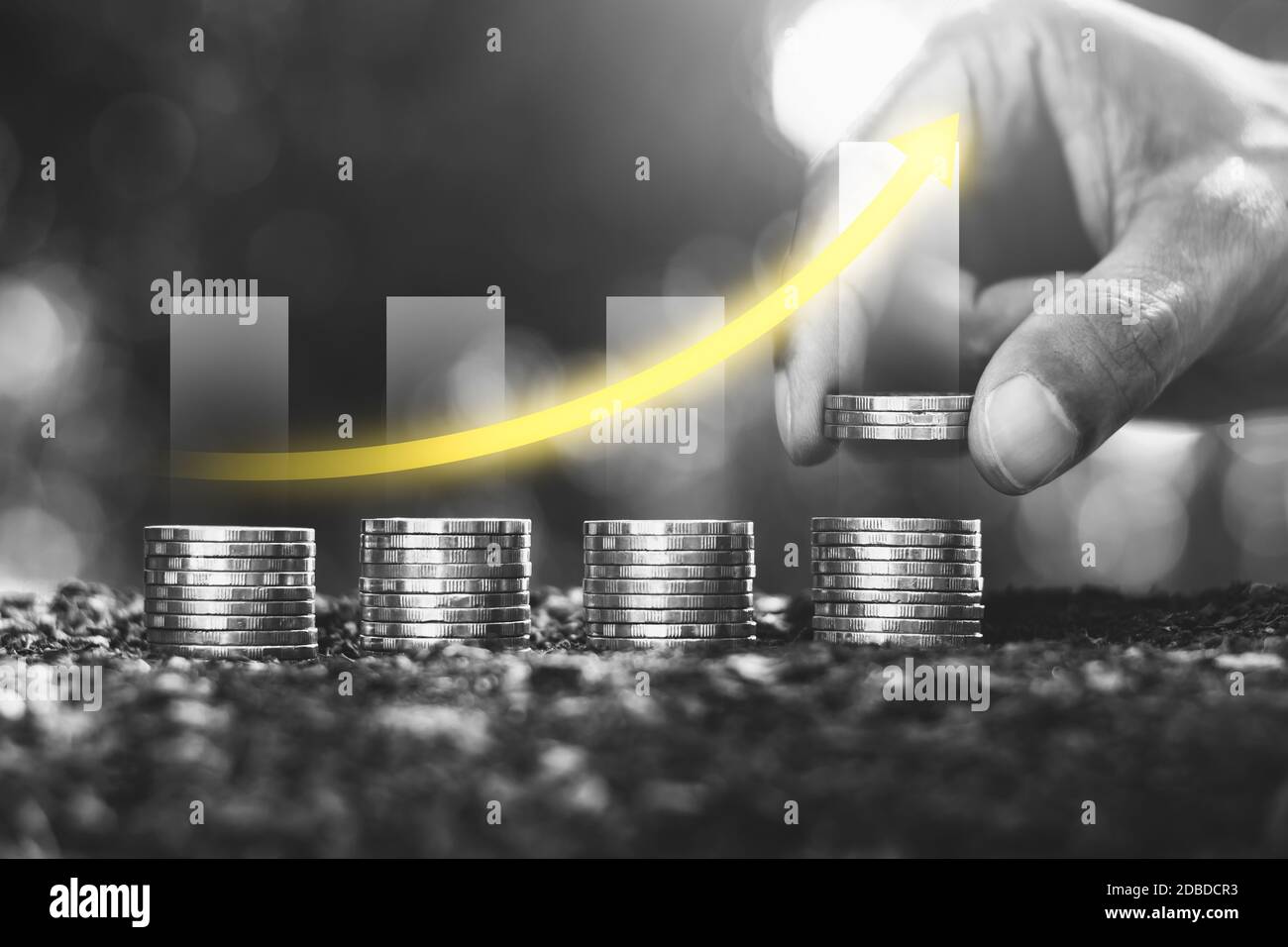 Le mani degli uomini stanno raccogliendo le monete accatastate sulla terra e ci è una tabella di crescita finanziaria sulla parte superiore. Foto Stock