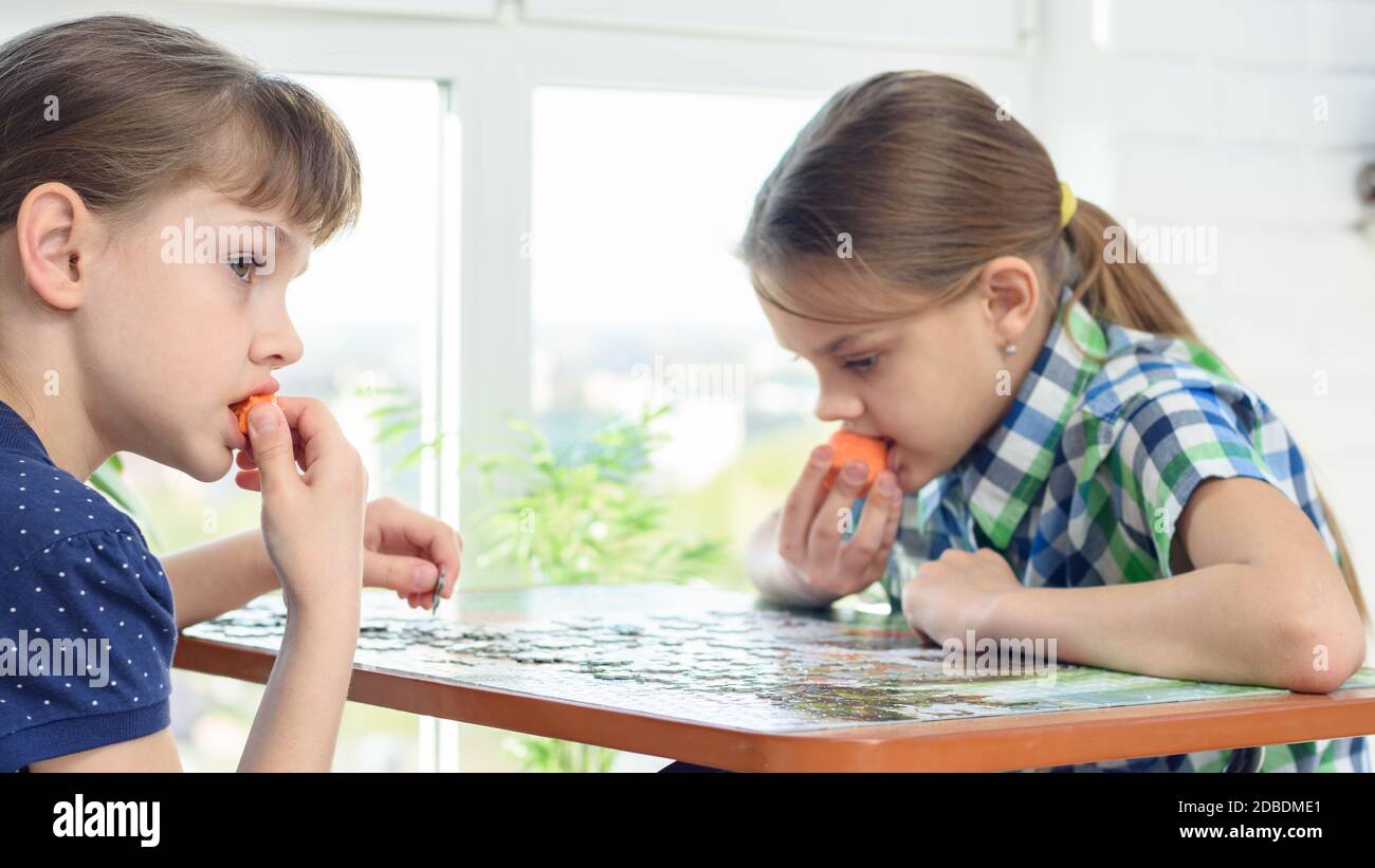 I bambini raccolgono puzzle e snack sulle carote Foto Stock