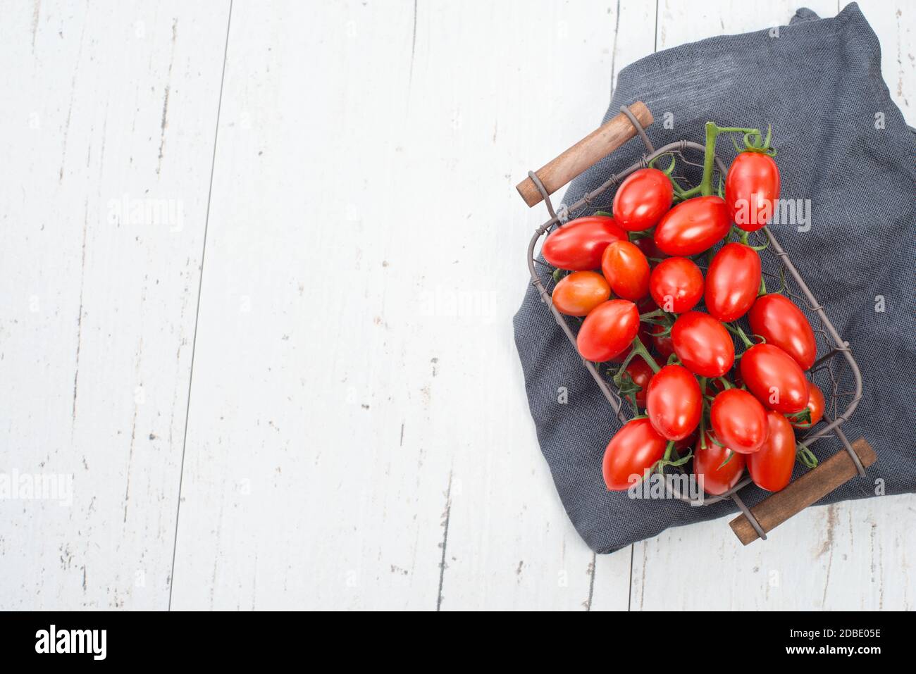 Pomodori ciliegini rossi su sfondo shabby bianco, spazio copia vuoto Foto Stock