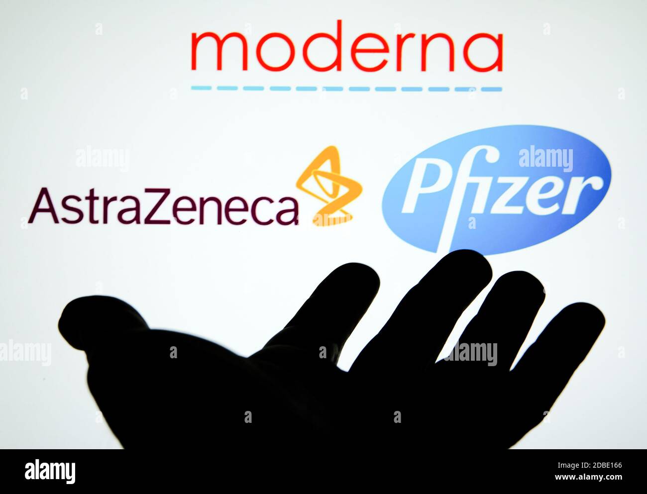 Silhouette di una mano aperta con logo dello sviluppatore di vaccini COVID sfocati sullo sfondo. Concetto per il vaccino moderna, AstraZeneca e Pfizer COVID-19. Foto Stock