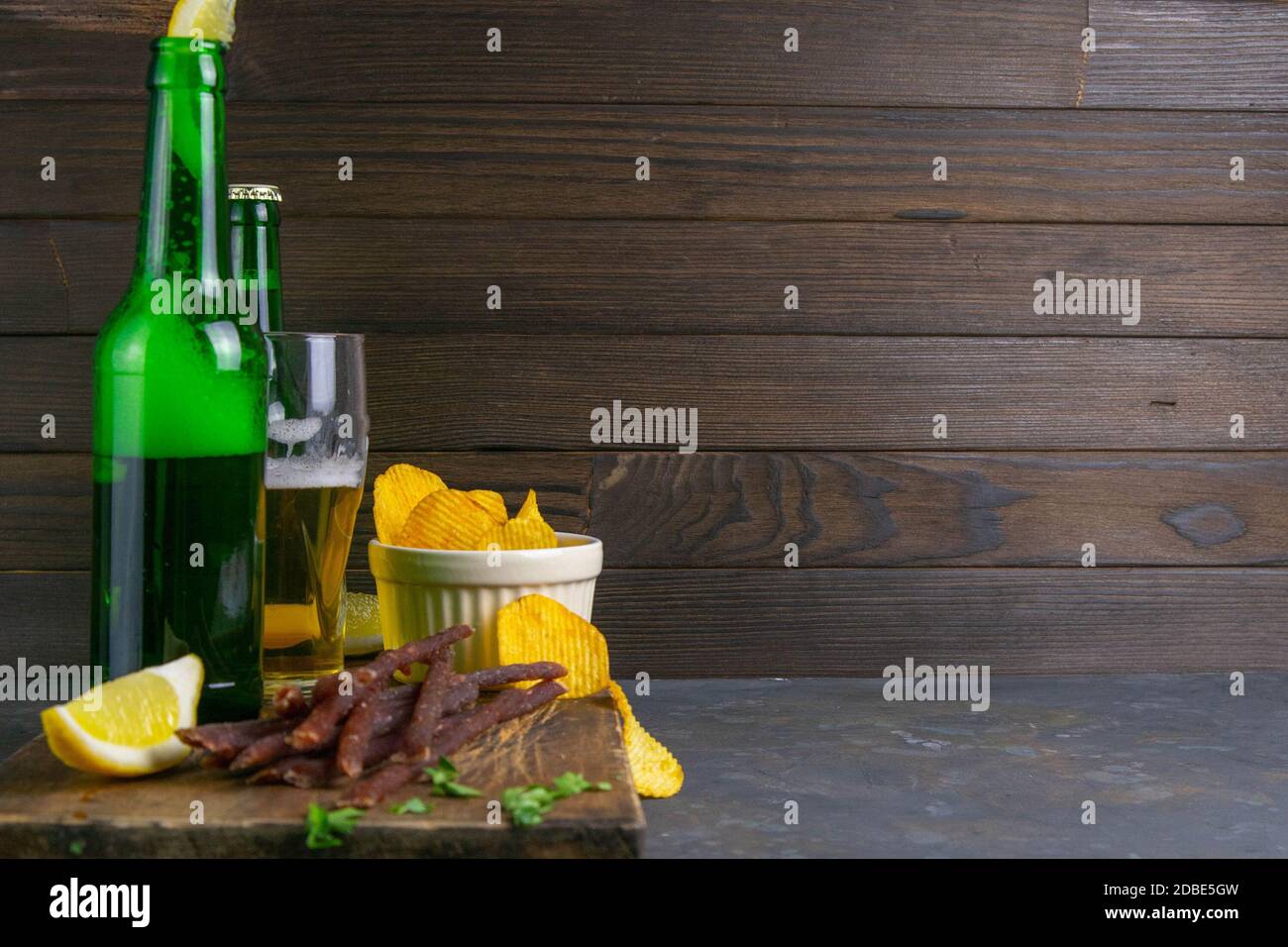 Spuntino al caviale di pesce con birra, limoni e patatine su tavola di legno scuro. Spuntino a base di pesce con birra. Vista frontale con spazio libero. Foto Stock